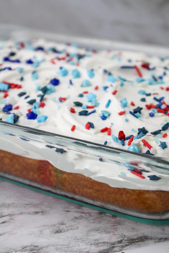 iced and decorated 4th of july poke cake in a glass baking dish