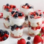 four jars of summer berry trifle on a white table