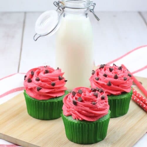 three watermelon cupcakes on a wooden cutting board