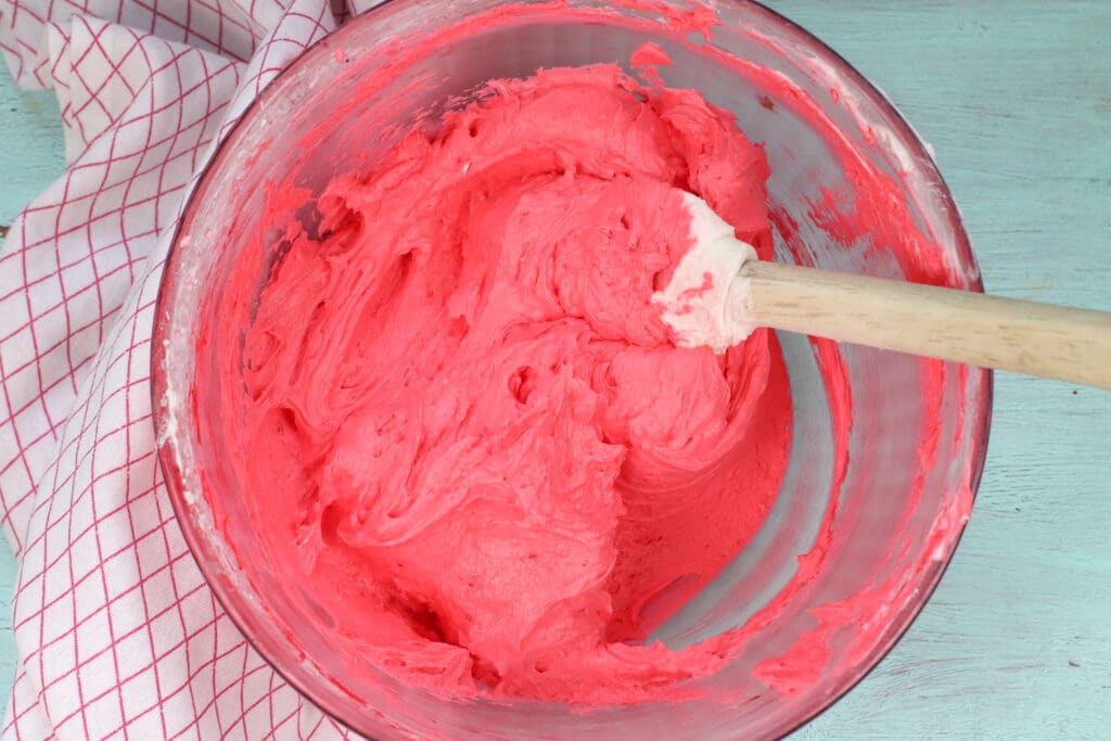 pink frosting in a glass mixing bowl