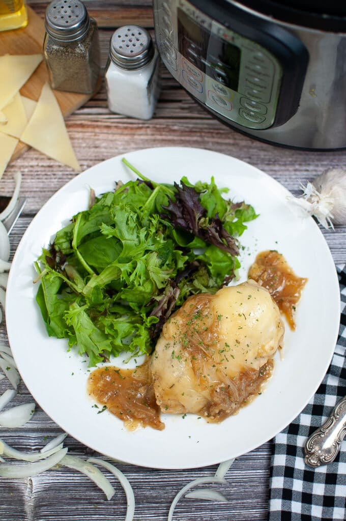 birds eye image of french onion chicken on a white plate with a side salad