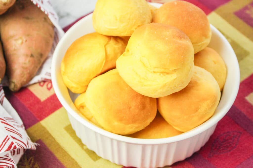 close up of a white bowl filled with bread machine sweet potato rolls