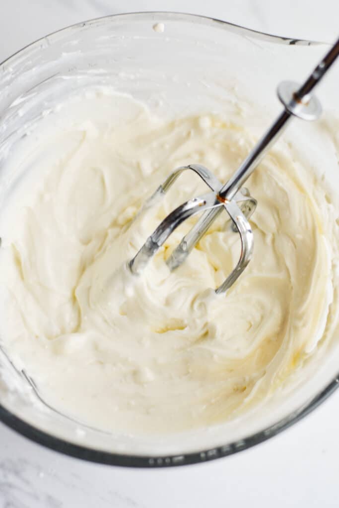 cream cheese and yogurt mixed together in a glass mixing bowl