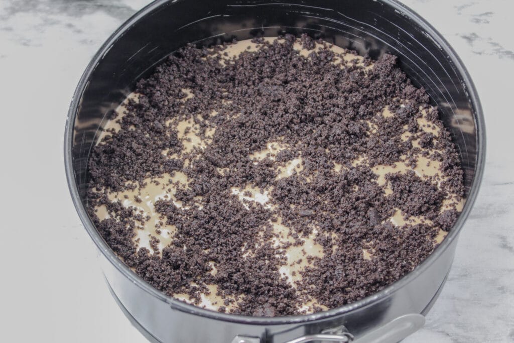 crushed oreo cookies on top of nutella cheesecake batter in a springform pan