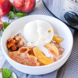 white bowl filled with slow cooker peach cobbler