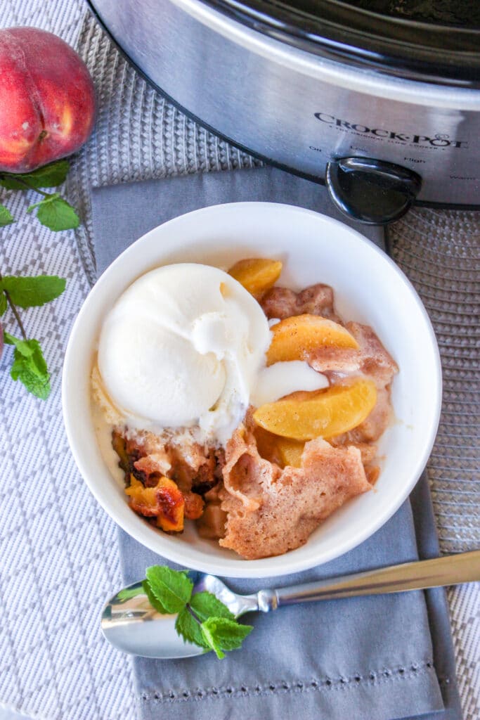 birds eye image of a white bowl filled with slow cooker peach cobbler