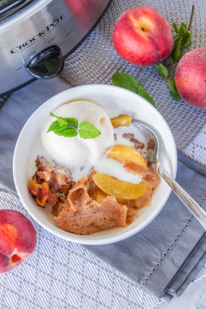 birds eye image of white bowl filled with slow cooker peach cobbler