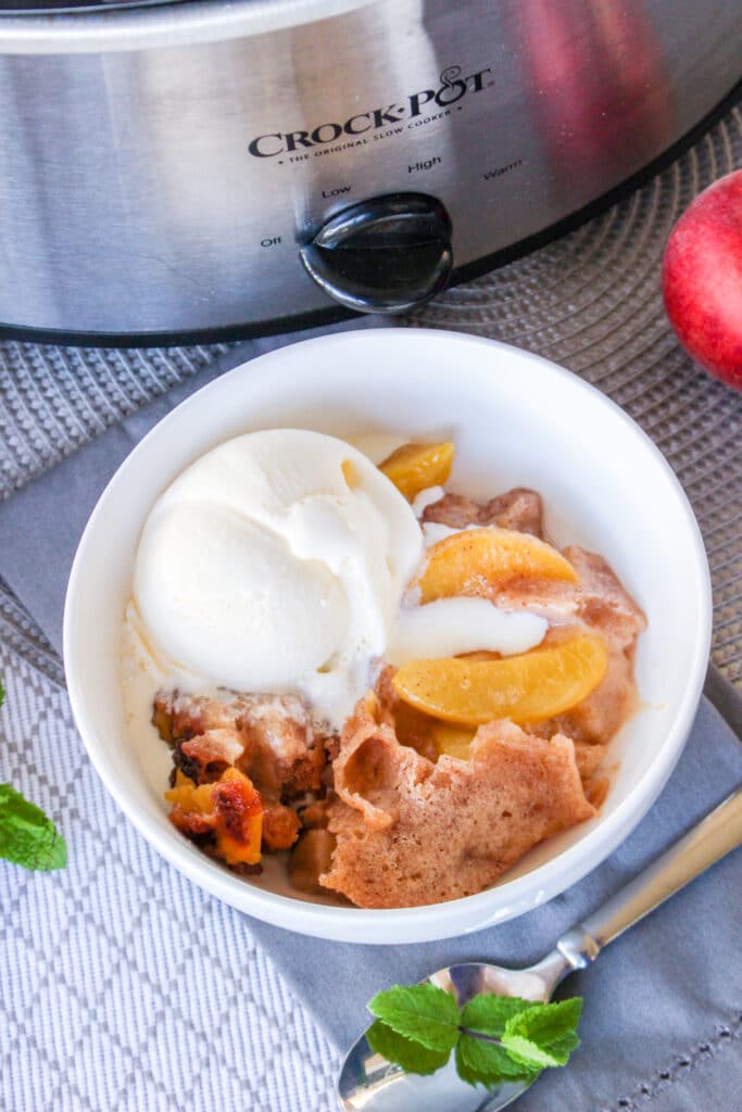 birds eye image of white bowl filled with slow cooker peach cobbler