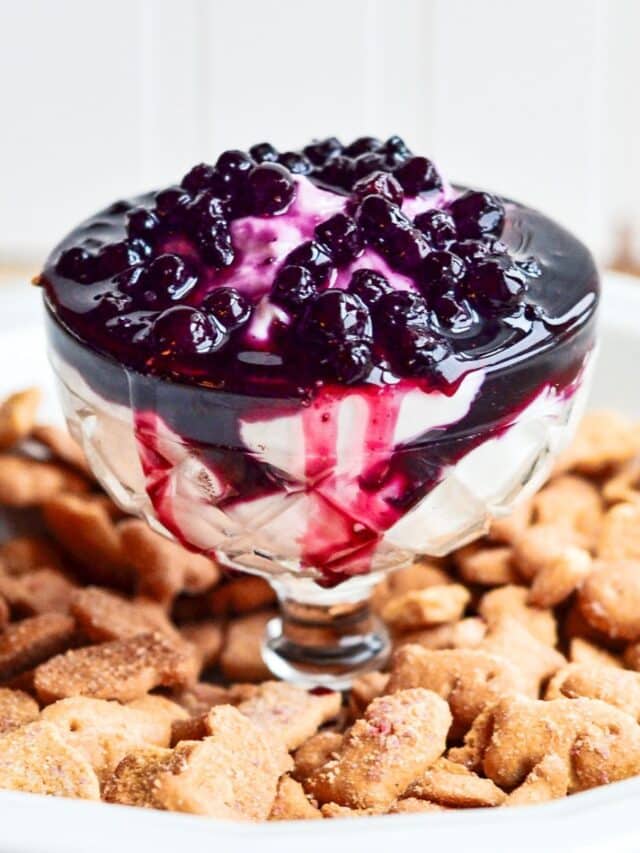 close up of a glass serving dish filled with blueberry cheesecake dip