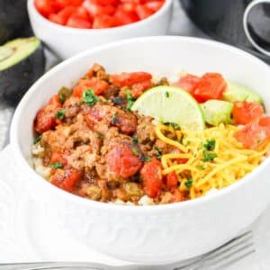 slow cooker carne picada in a white bowl on top of rice