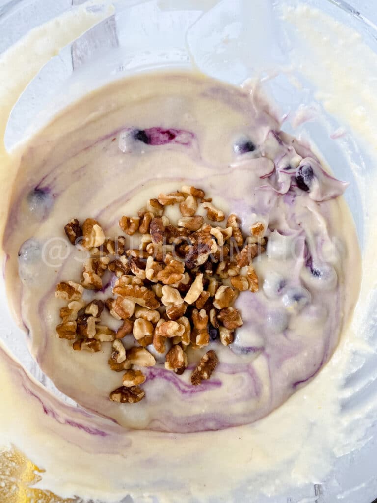 blueberries and walnuts being folded into batter