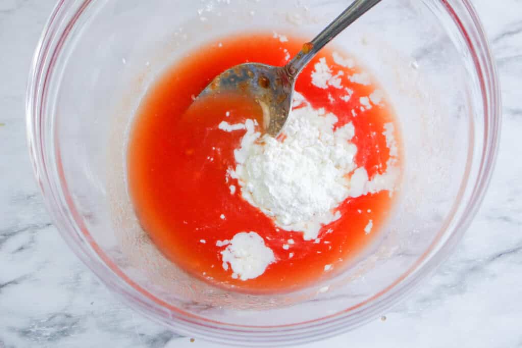 tomato juice and cornstarch being mixed in a glass bowl