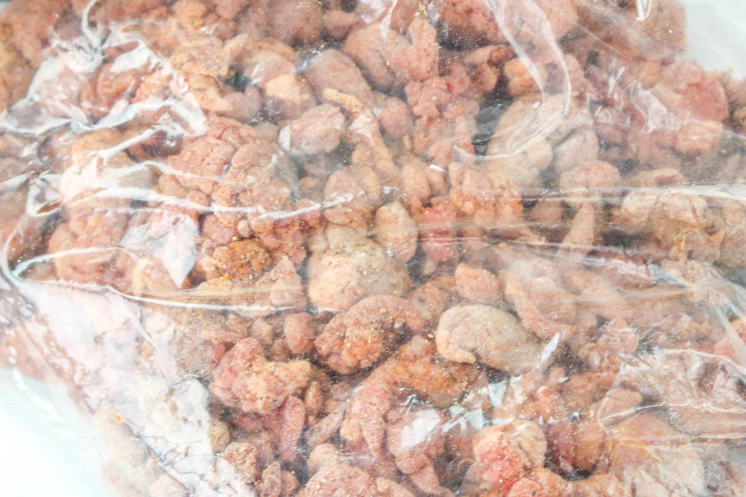 beef being coated in flour in a storage bag