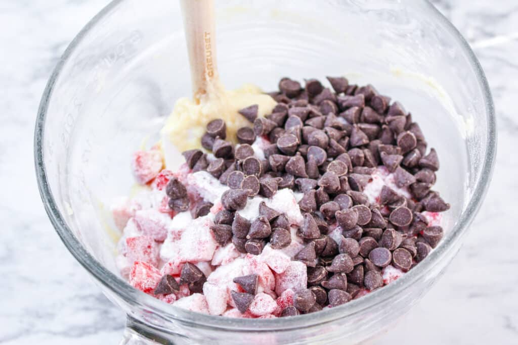 strawberries and chocolate chips being mixed into a large mixing bowl
