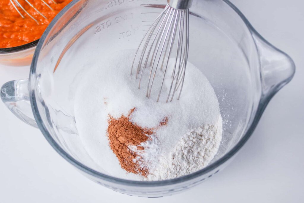 sugar, flour, and pumpkin pie spice in a glass mixing bowl