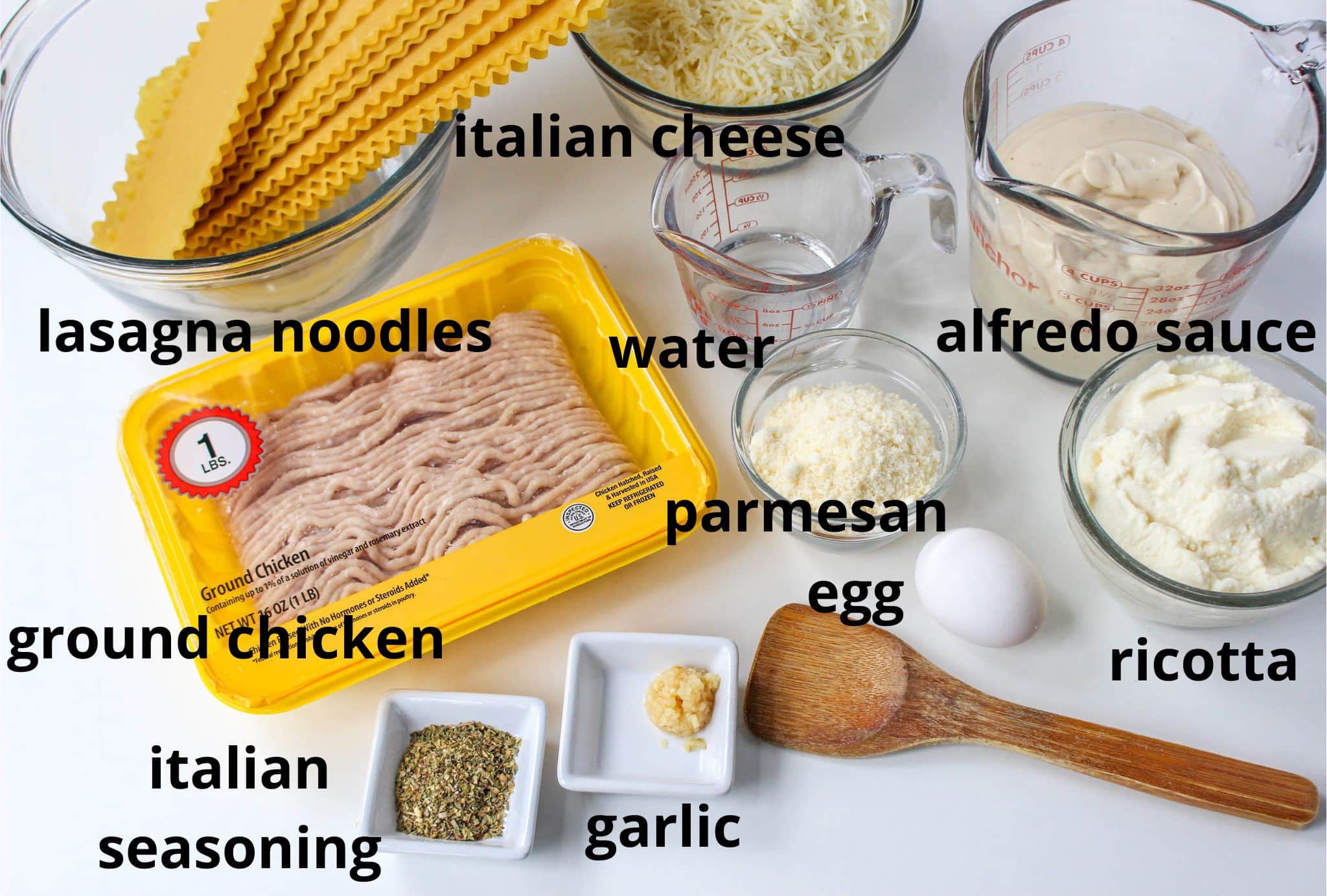 italian cheese, alfredo sauce, lasagna noodles, ground chicken, water, parmesan, egg, ricotta, italian seasoning, and garlic on a white table