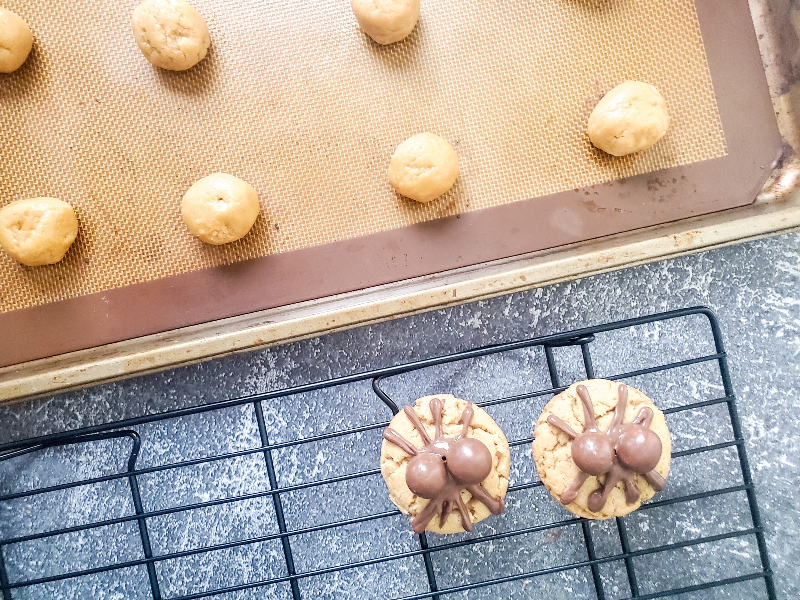 unbaked cookies on a baking sheet and two finished cookies on a cooling rack