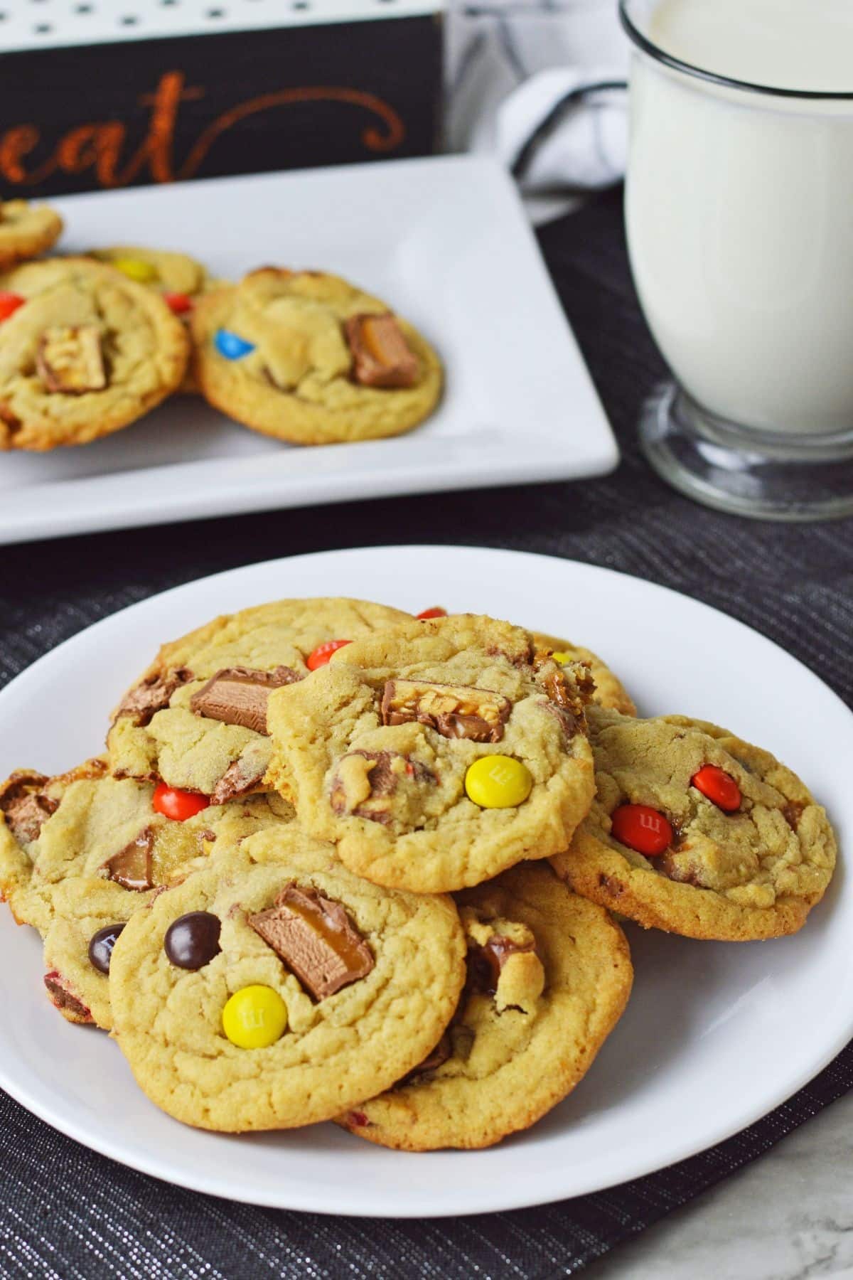 candy bar cookies on a white plate with a mug of milk in the background