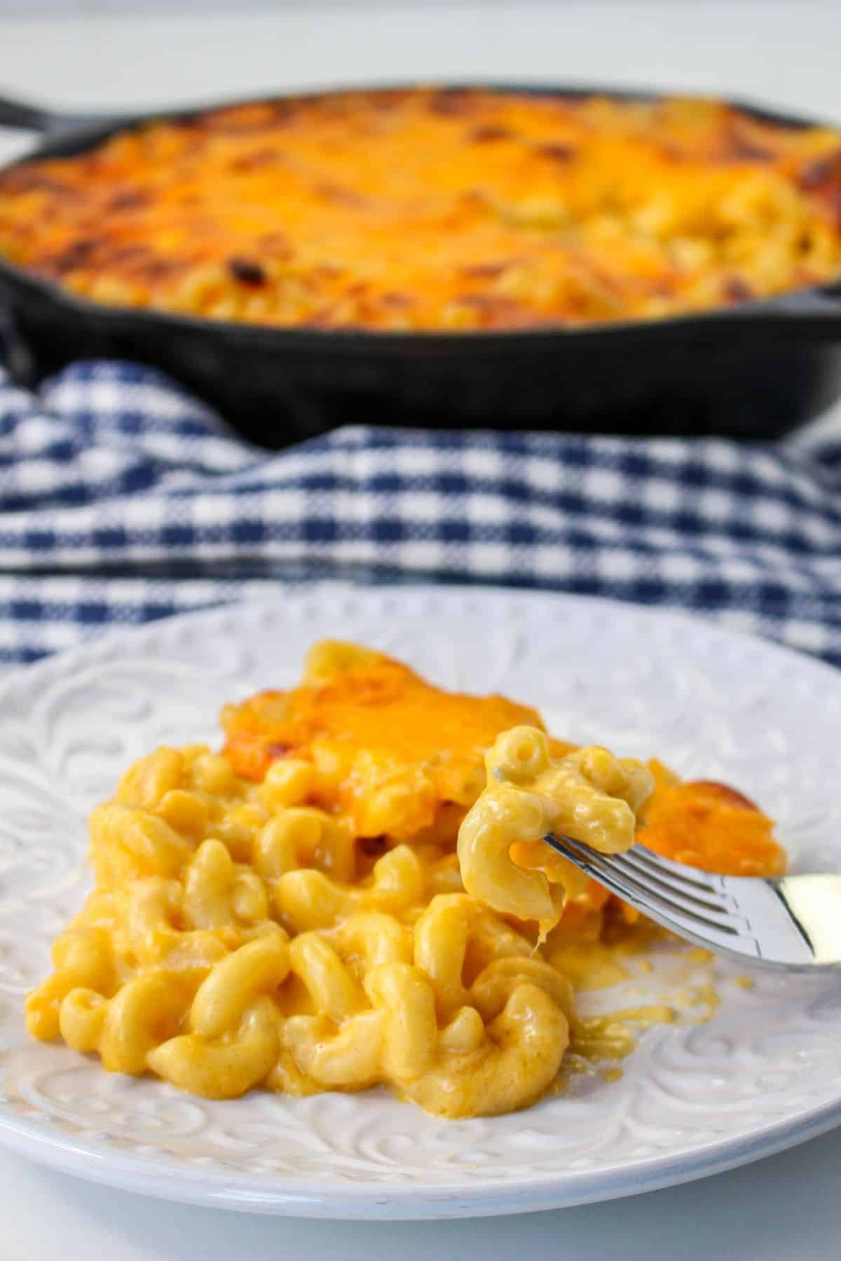 Cast Iron Skillet Mac and Cheese on a white palte with the full skillet in the background