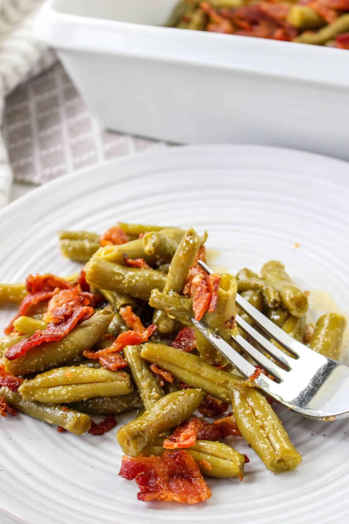 crack green beans on a white plate with a bite on a fork
