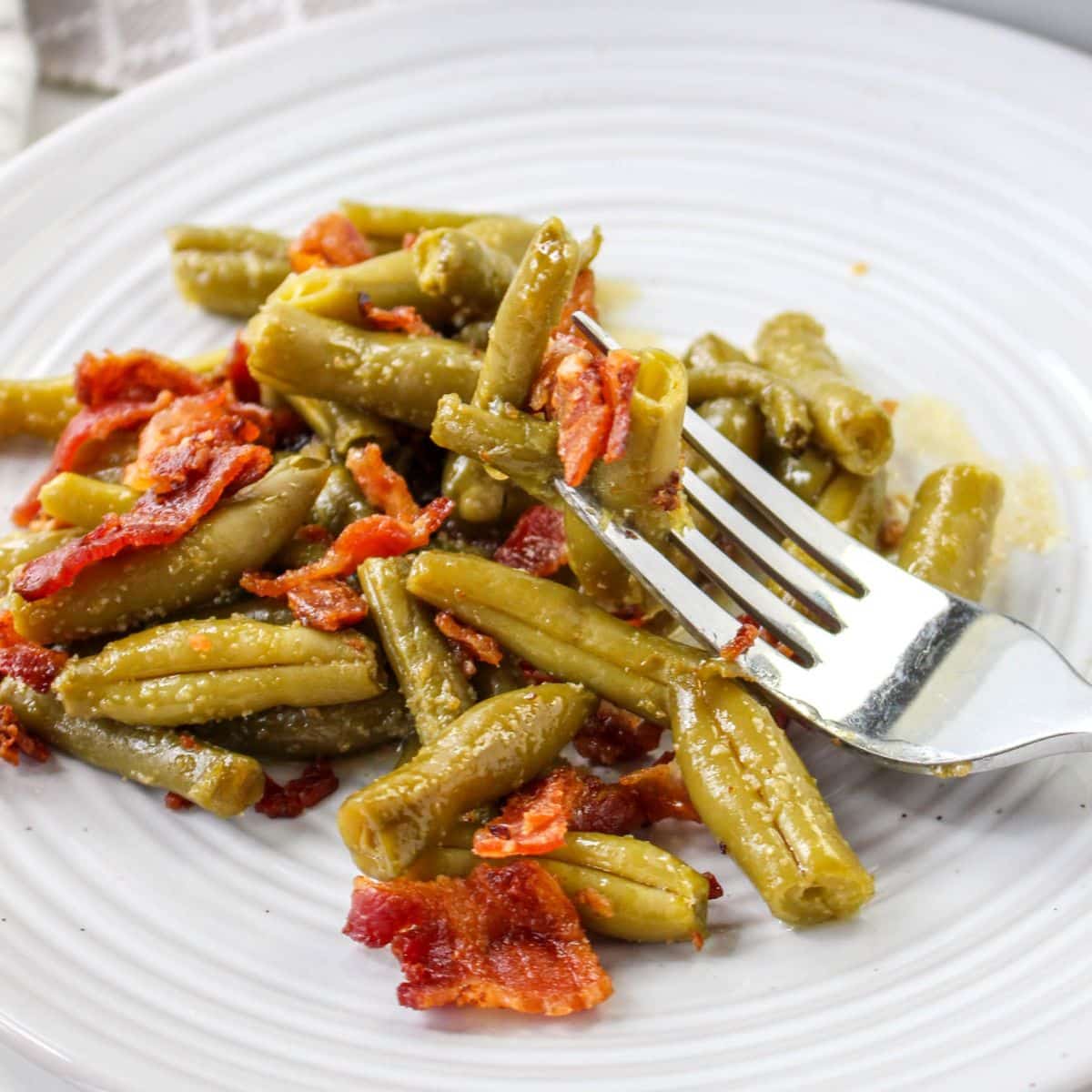 crack green beans on a white plate with a bite on a fork