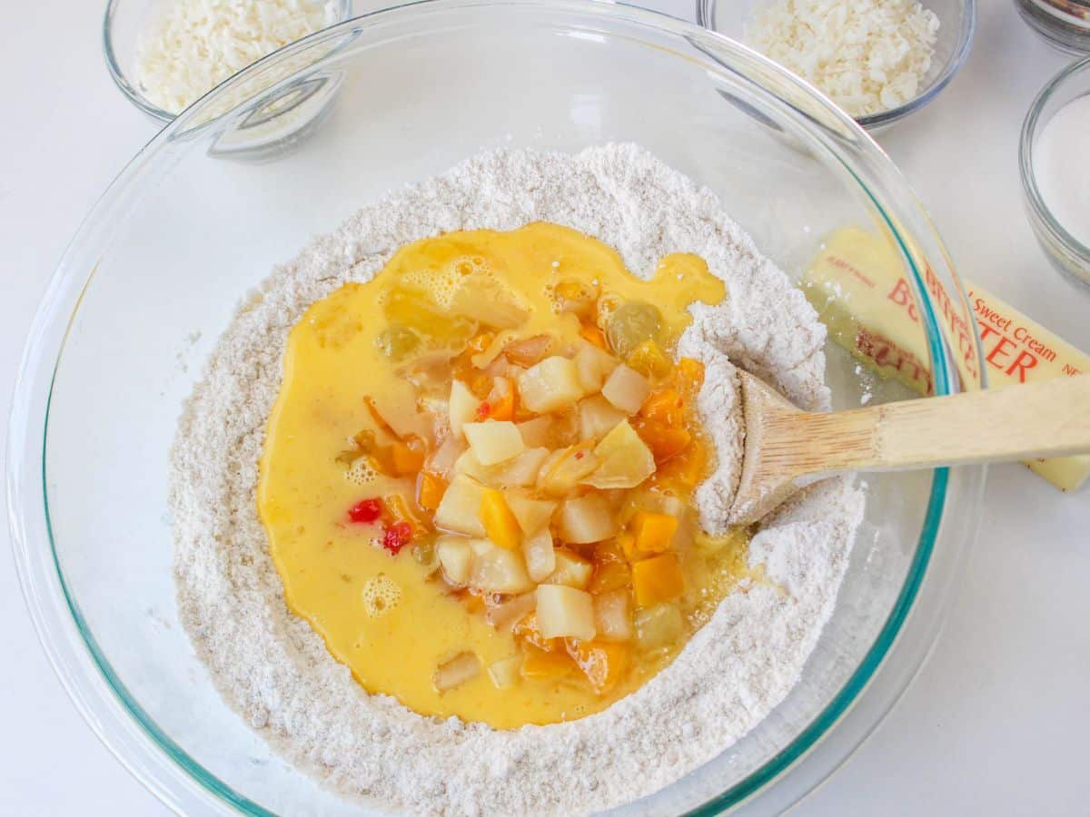 fruit, flour and sugar in a glass mixing bowl
