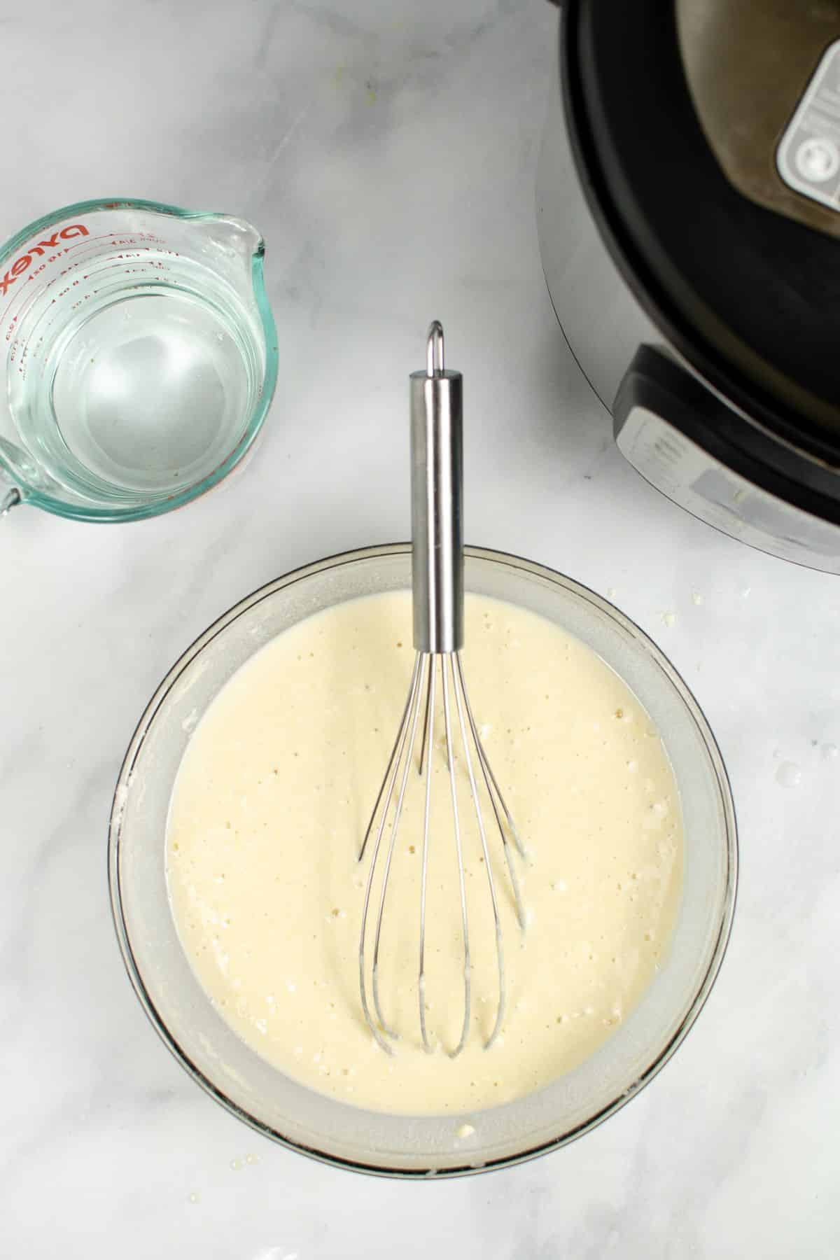 batter in a glass mixing bowl with a stainless steel whisk