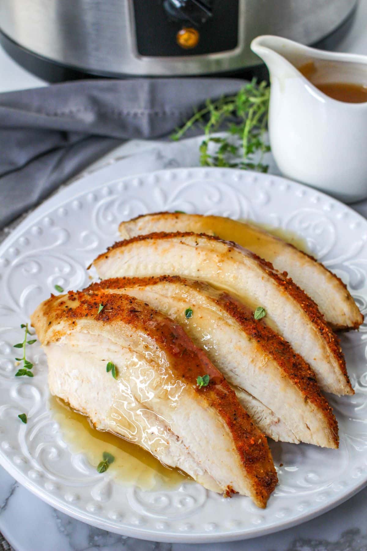 close up image of four slices o cajun turkey breast on a white plate topping with gravy