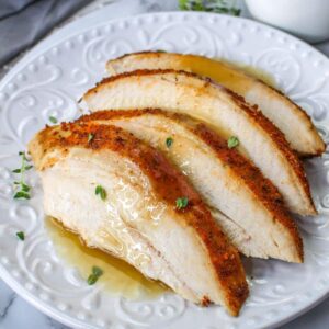 close up image of four slices o cajun turkey breast on a white plate topping with gravy