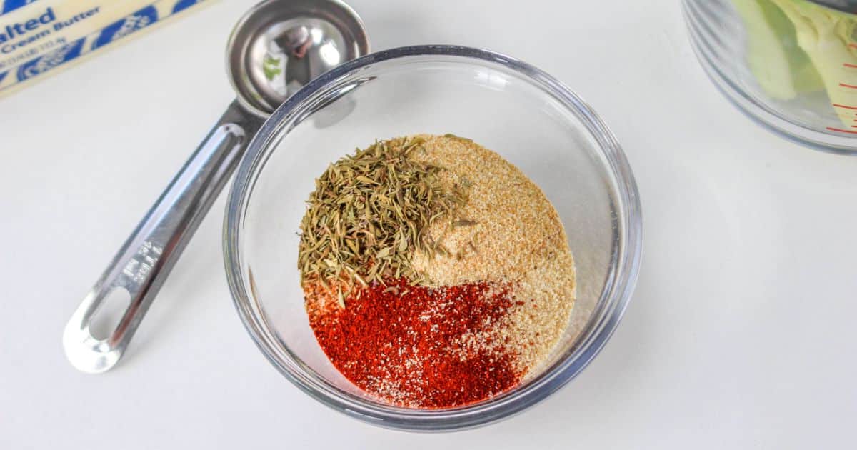 seasonings in a small glass bowl with a measuring spoon next to it.
