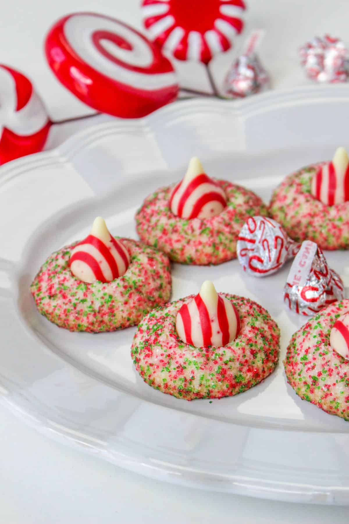 off center image of a white plate with candy cane shortbread cookies and candy cane hershey kisses on it