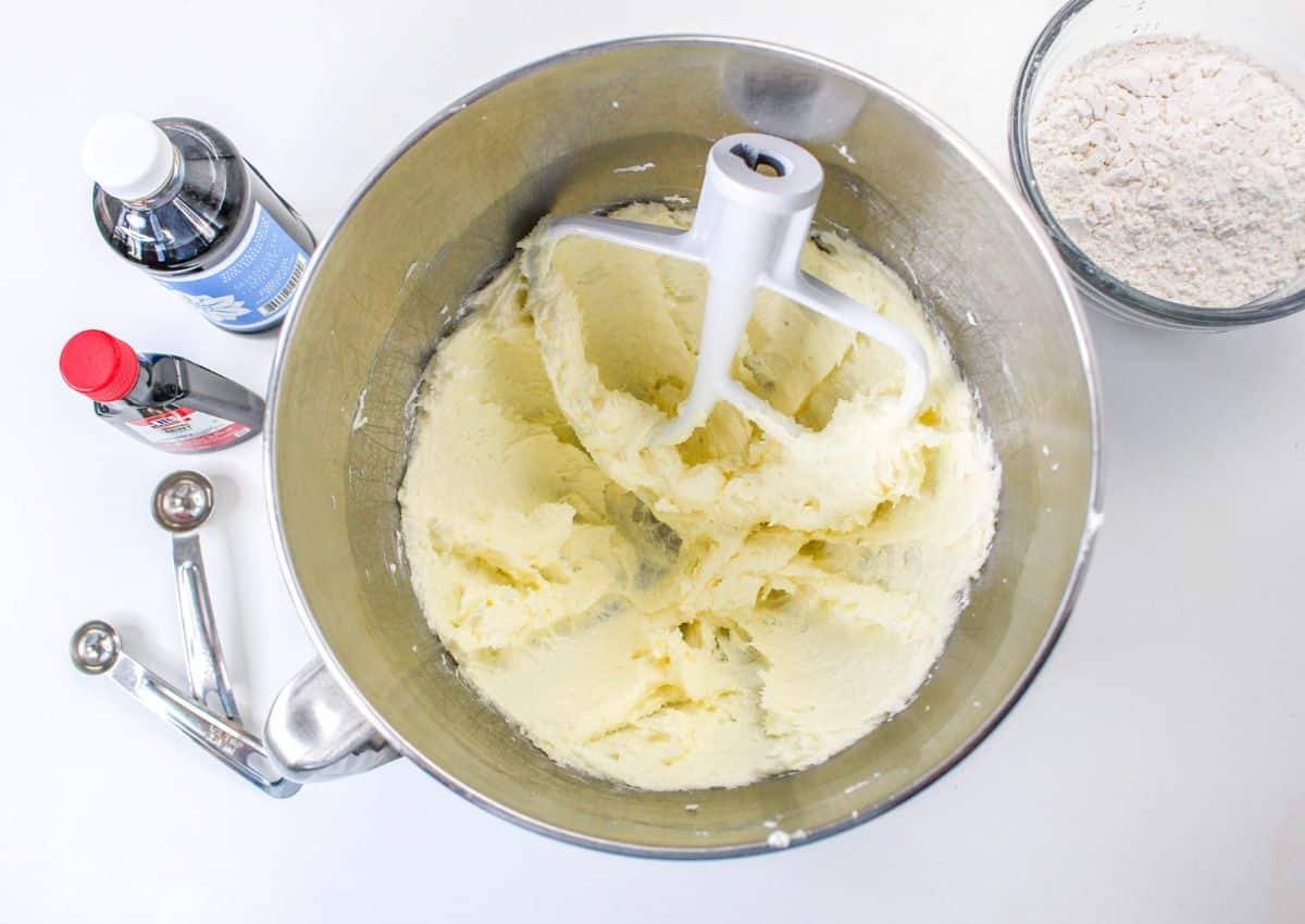 butter being creamed with a mixer in a stainless steel mixing bowl