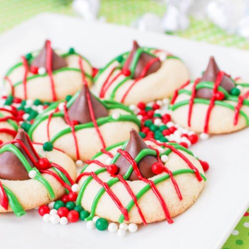 christmas blossom cookies on a white square plate with round red, white and green sprinkles