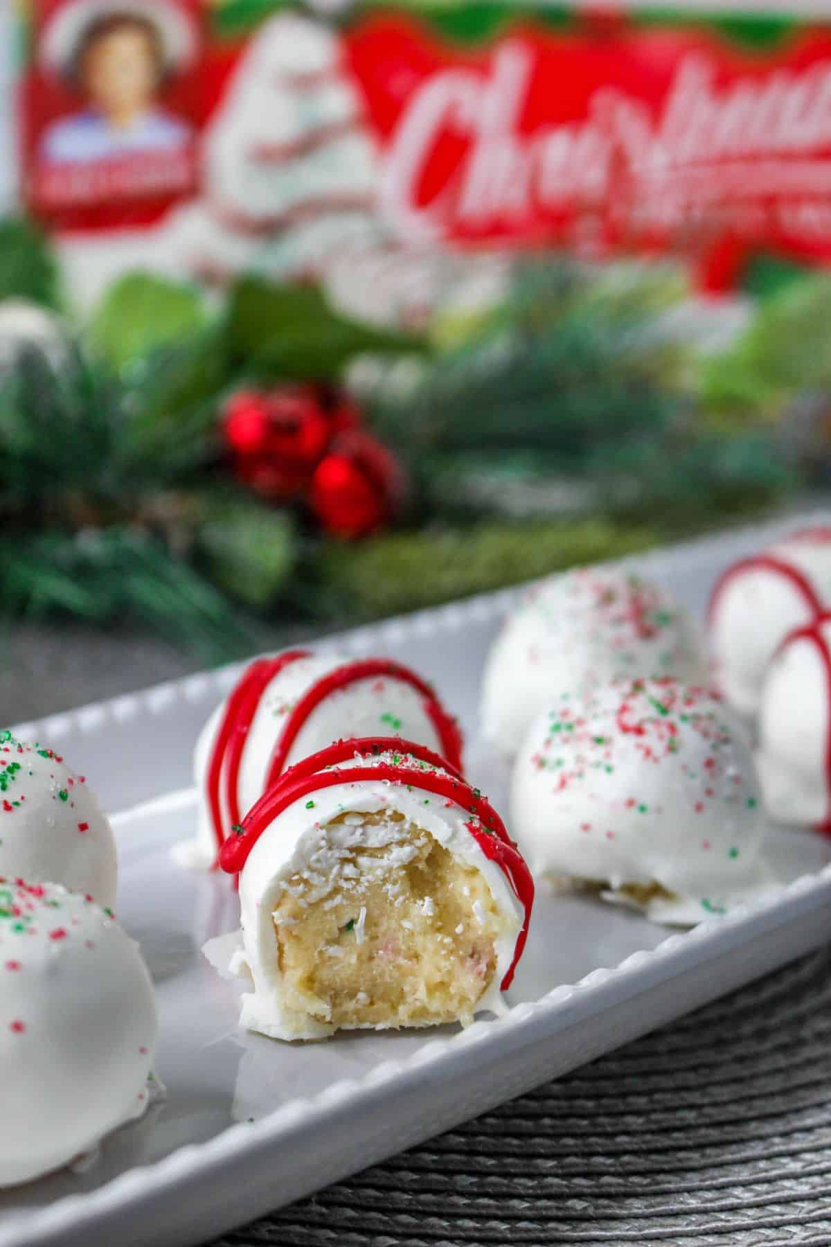 christmas tree cake balls on a white plate with one ball bitten in half so you can see the inside