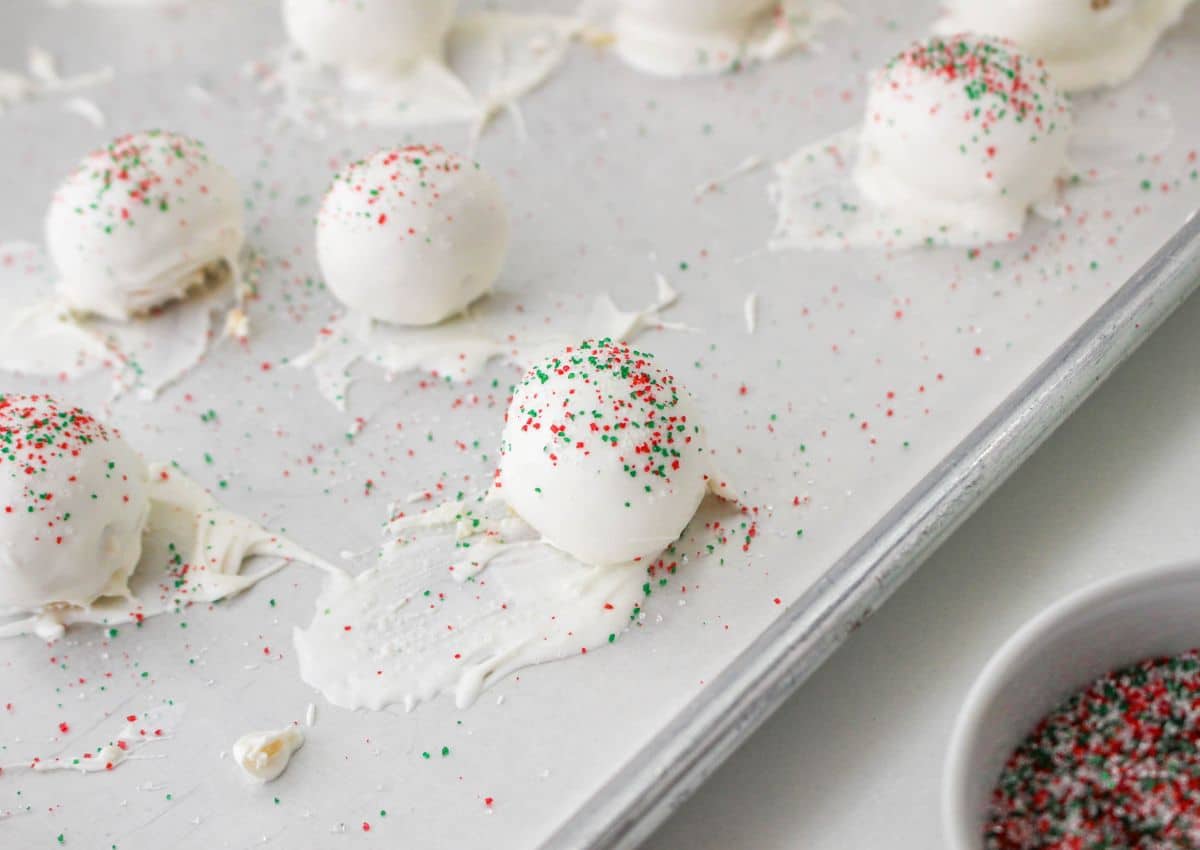 dipped christmas tree cake balls on a parchment lined baking sheet with sprinkles on top