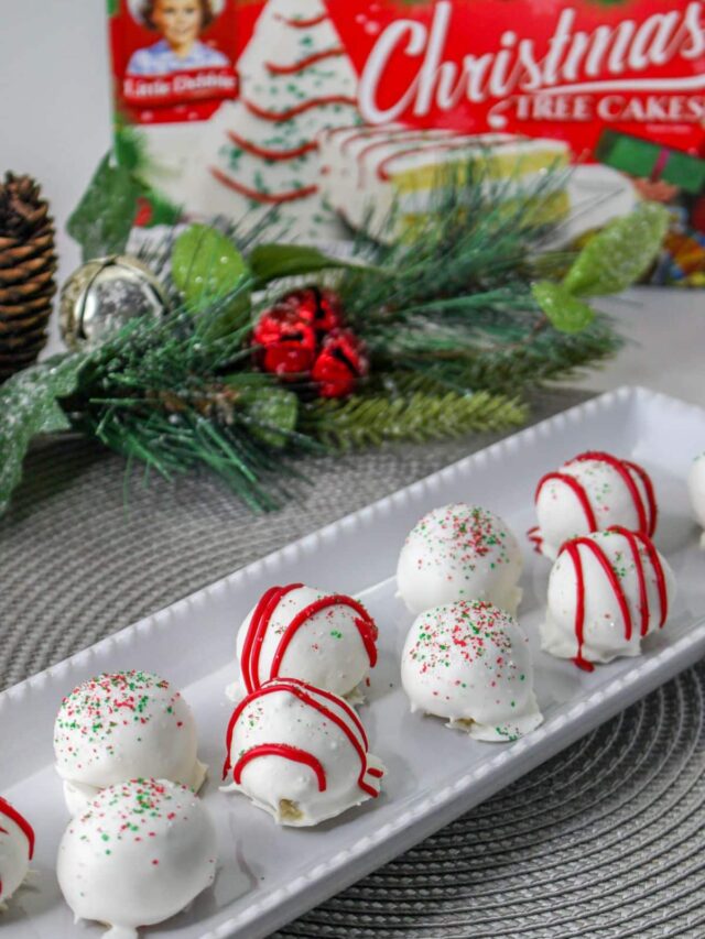 10 christmas tree cake balls on a white plate with a box of christmas tree cakes in the background