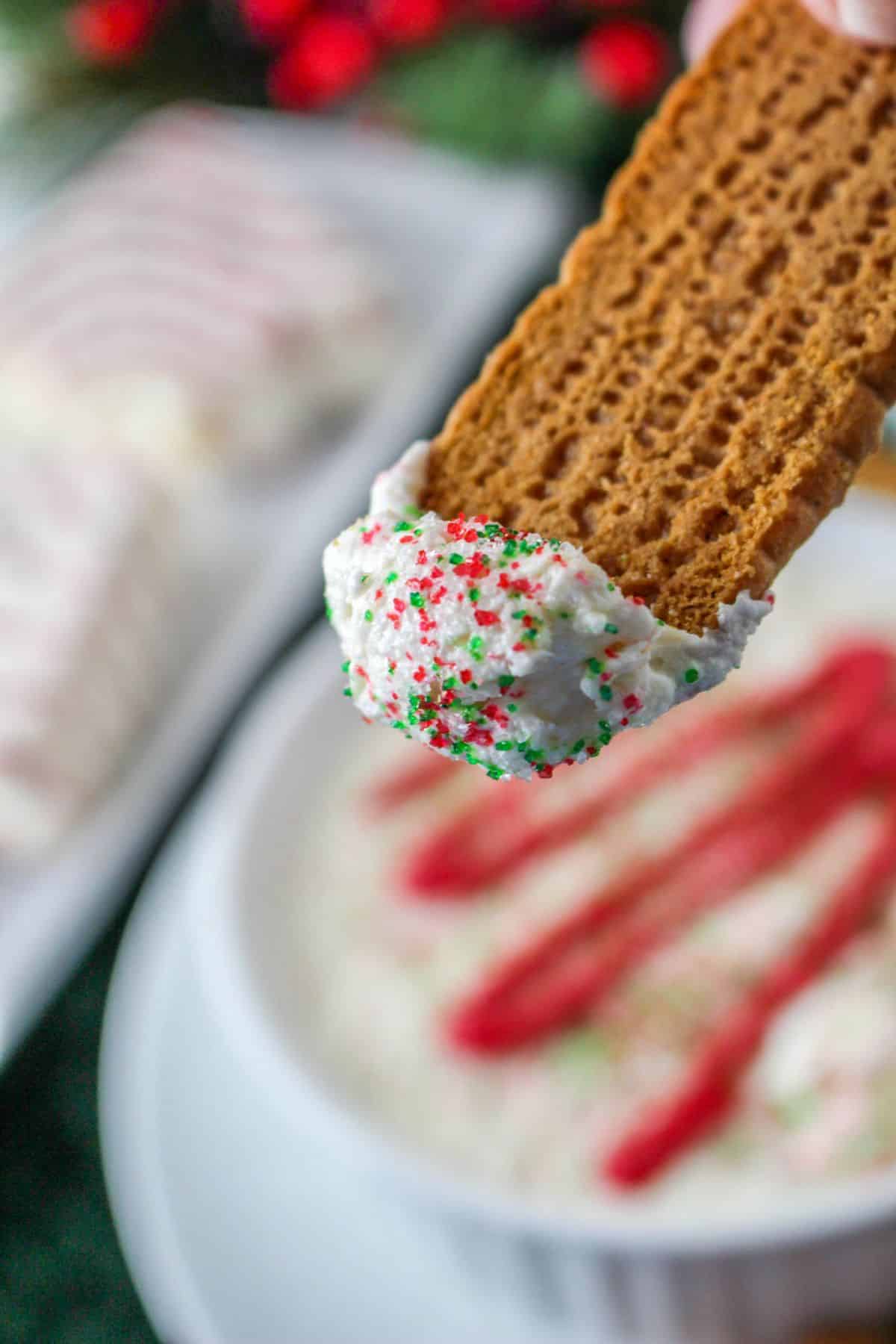 biscoff cookie with christmas tree dip on the tip of it, held in the air