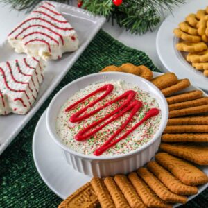 white bowl filled with christmas tree dip, with a plate with biscoff cookies on it