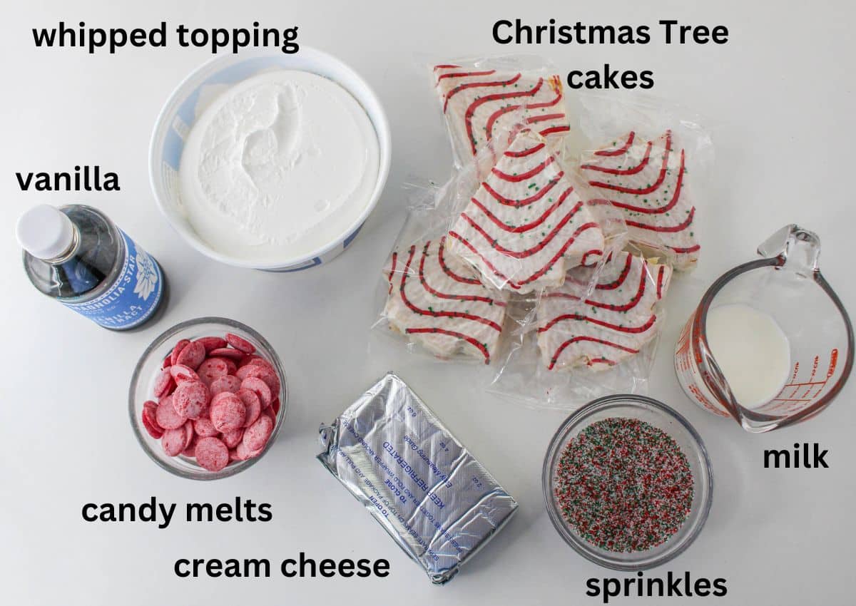 whipped topping, christmas tree cakes, milk, sprinkles, cream cheese, candy melts, and vanilla extract all labelled with text on a white background