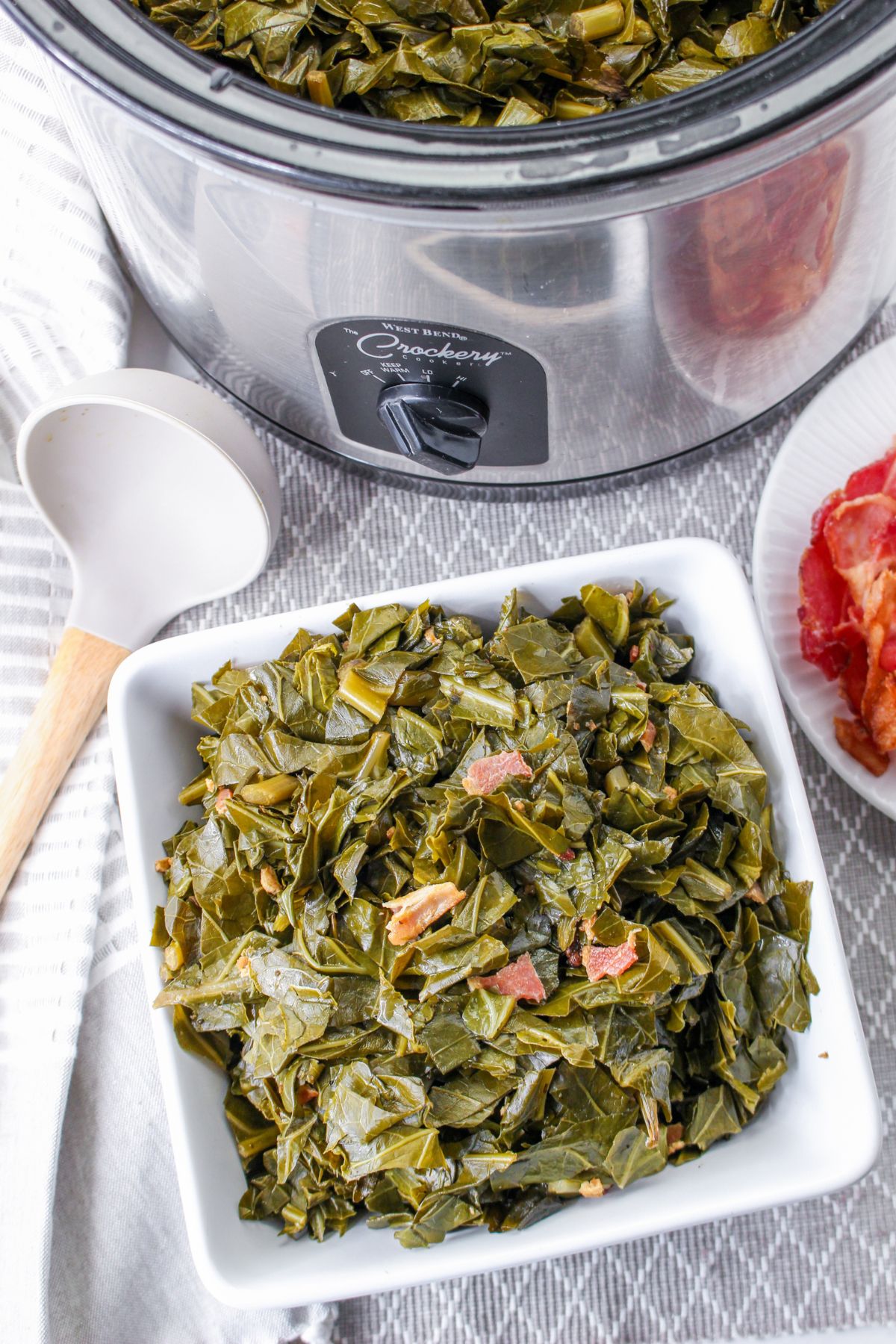 white bowl filled collard greens and a slow cooker in the background