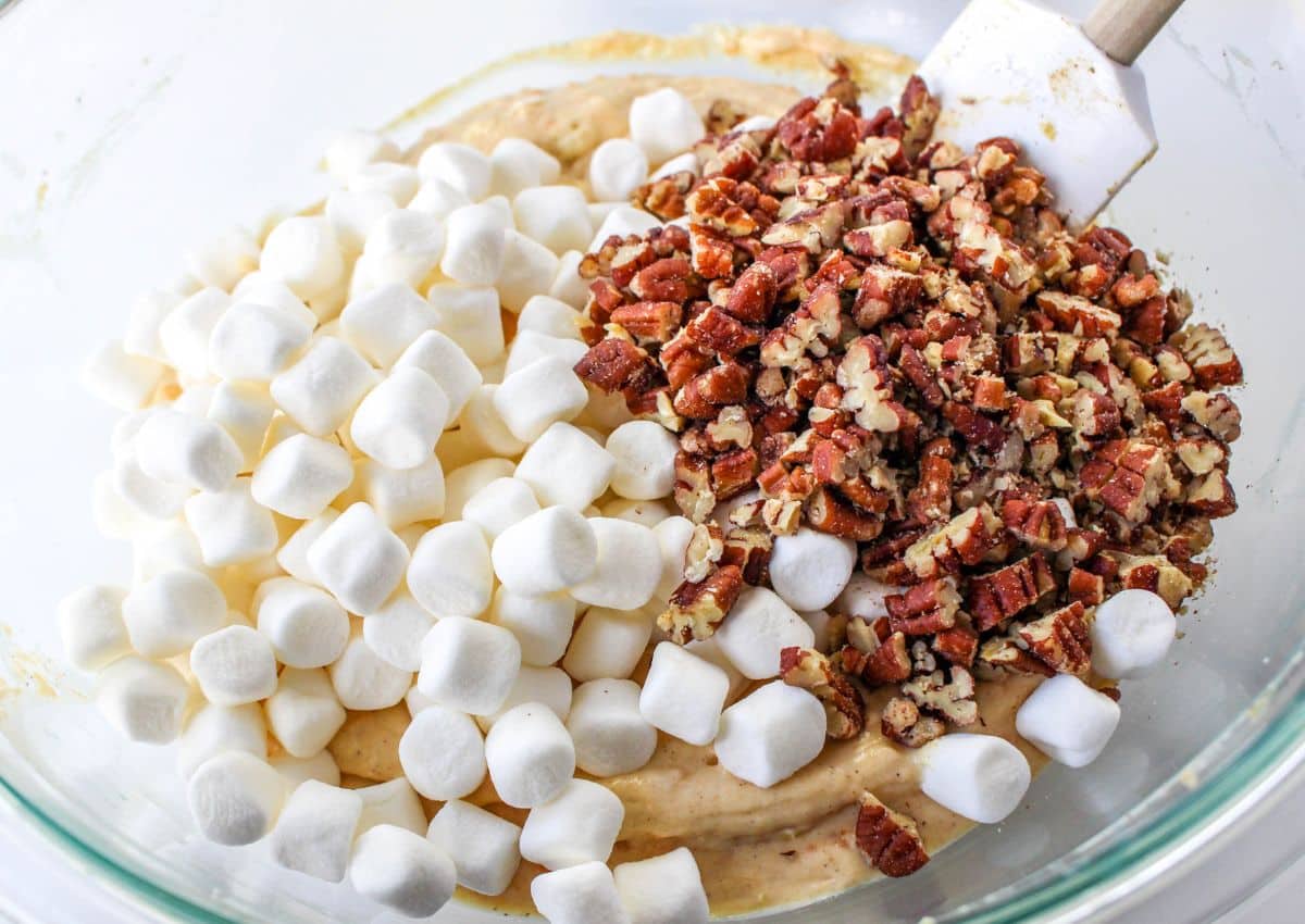 marshmallows and pecans being folding into a cream cheese mixture