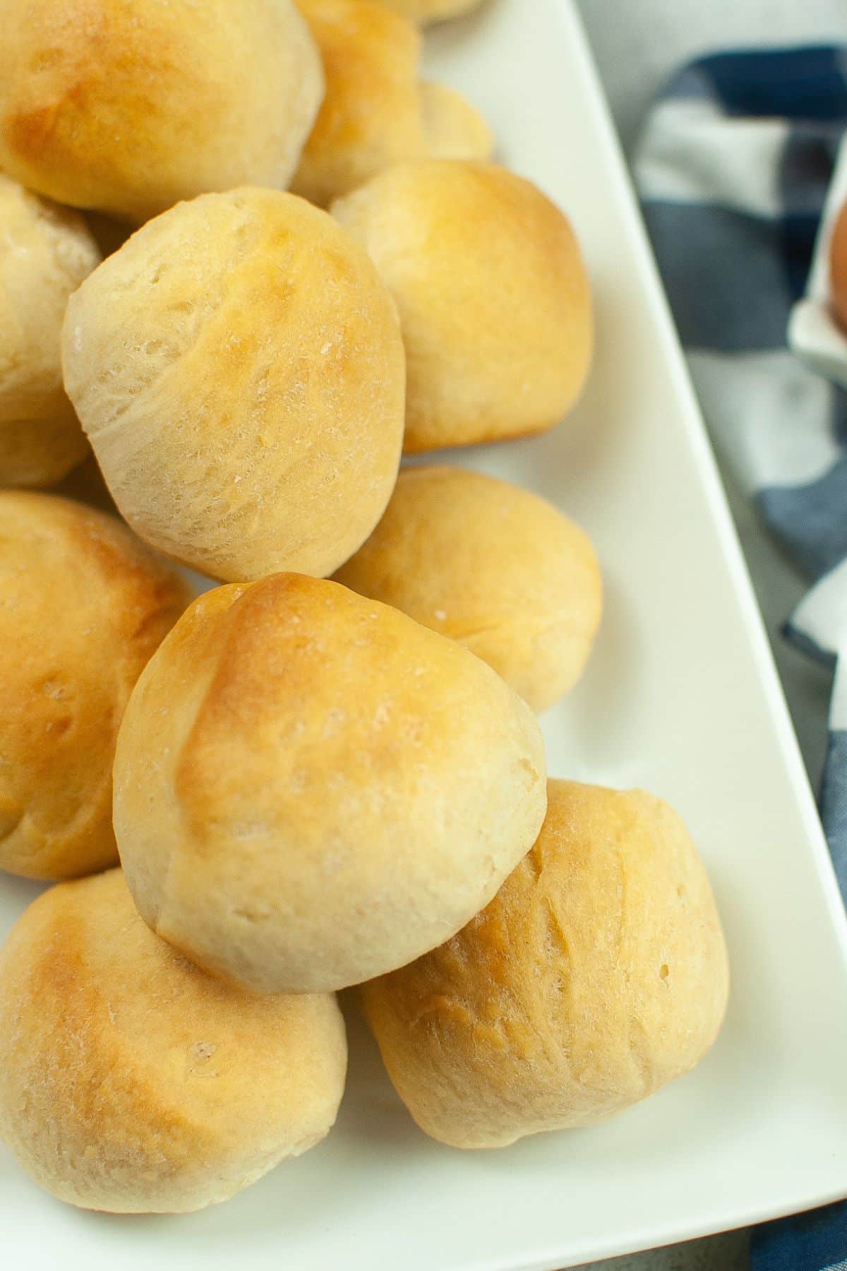 off center image of a stack of dinner rolls on a white rectangle platter