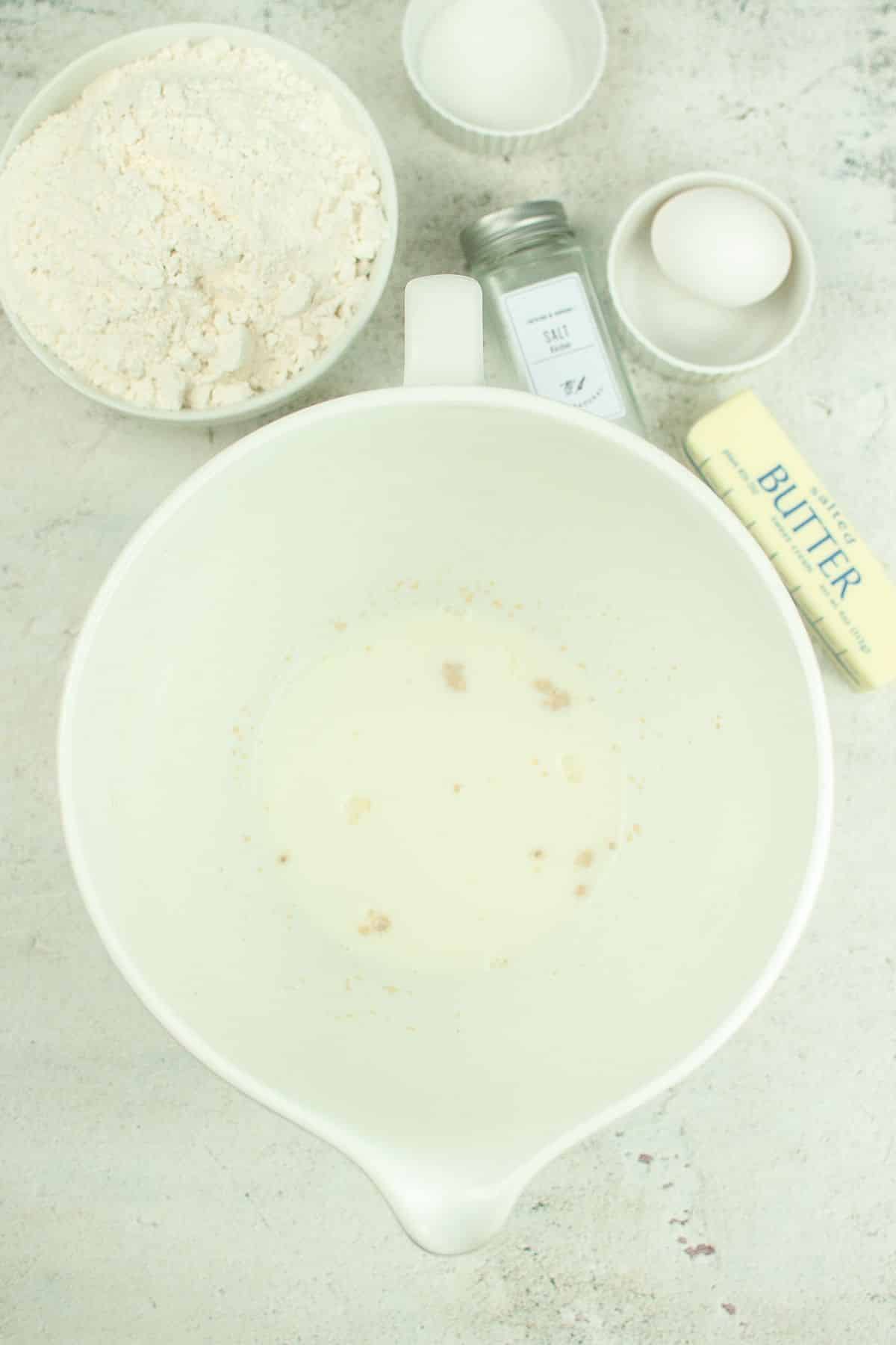 yeast and milk in a white mixing bowl on a textured background