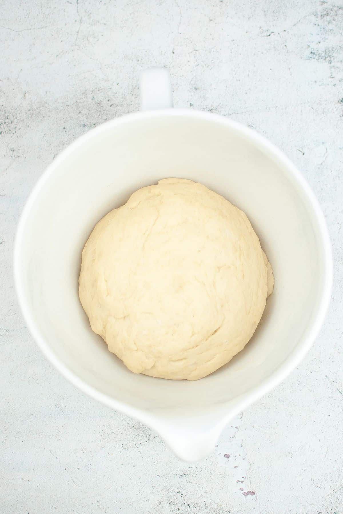 dough that has risen in a white mixing bowl