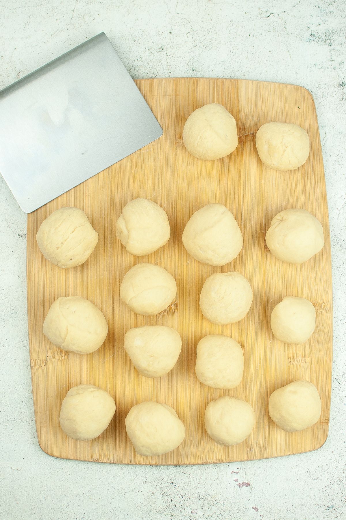 dough shaped into rolls on a wooden cutting board