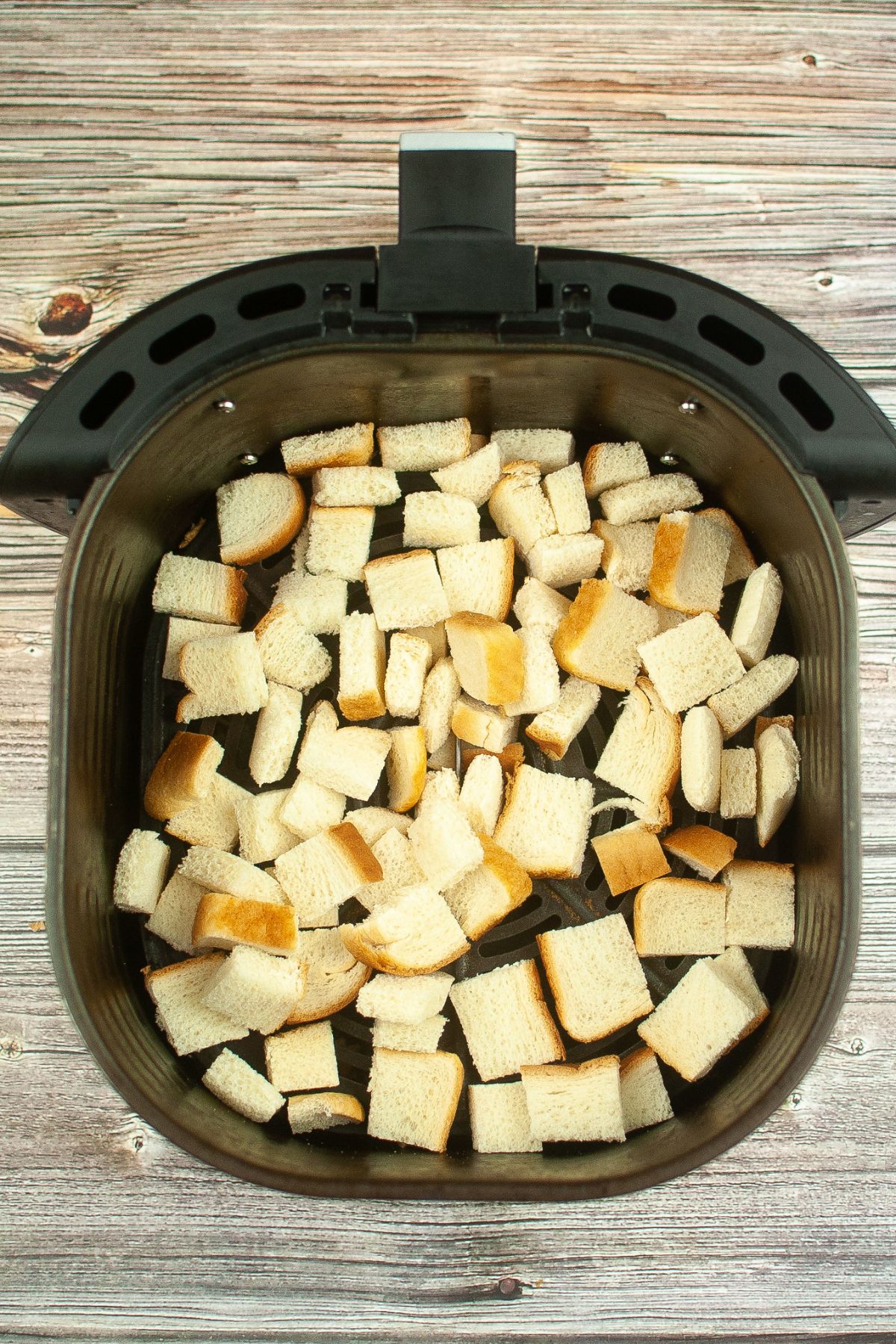 cubed slices of bread in an air fryer basket