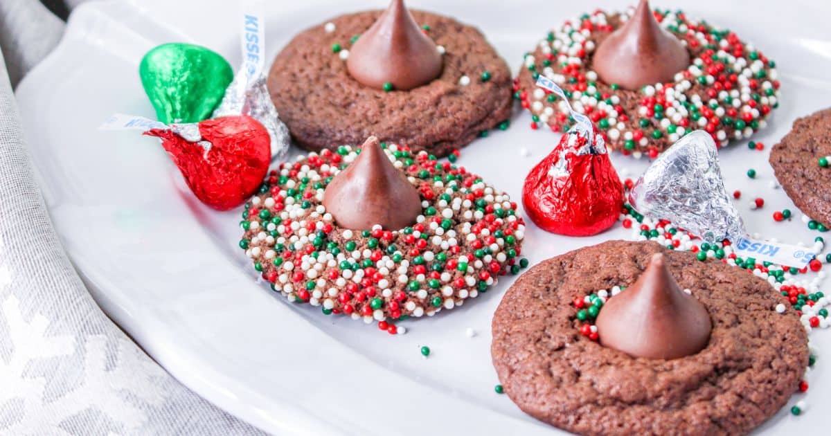 christmas blossom cookies on a white plate with a few hershey kisses