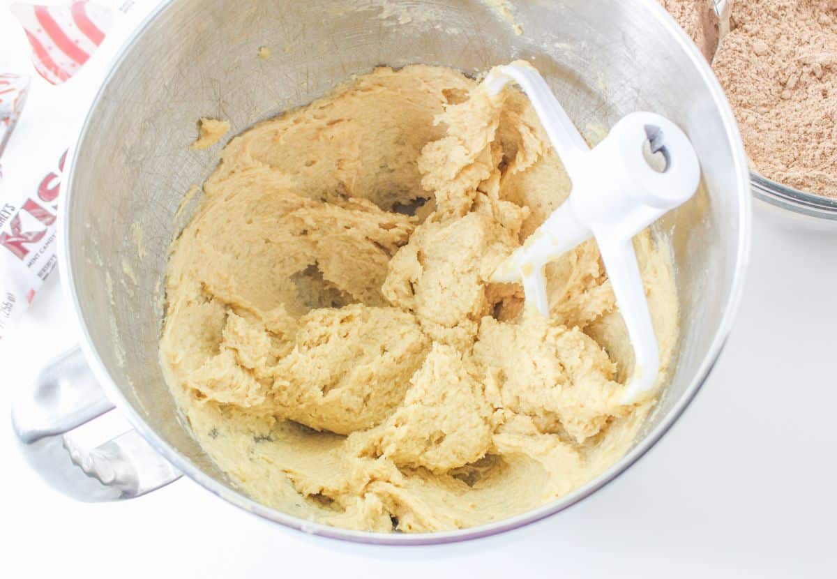 butter, sugar, and brown sugar being mixed in a stand mixer