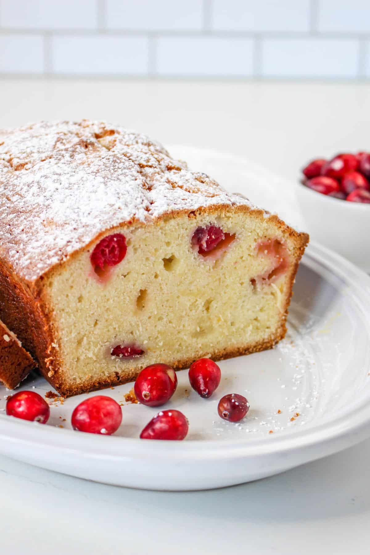 the inside of a loaf of christmas cranberry pound cake on a white serving platter