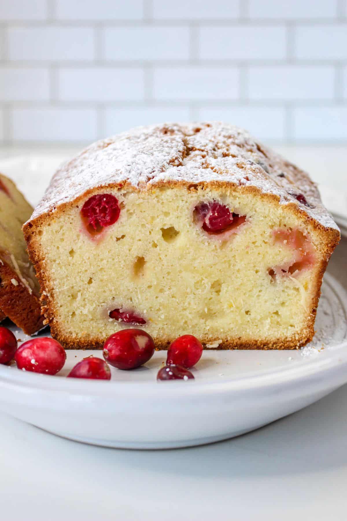 slice of christmas cranberry pound cake on a white plate with a few fresh cranberries